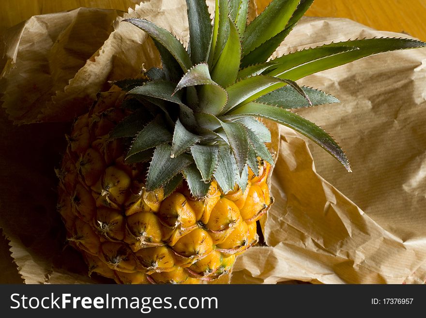 A whole yellow ripe pineapple fruit on a brown paper bag