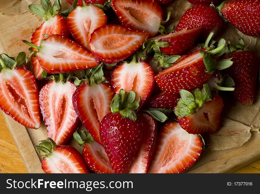 Fresh organic strawberry halves on a wooden cutting board. Fresh organic strawberry halves on a wooden cutting board