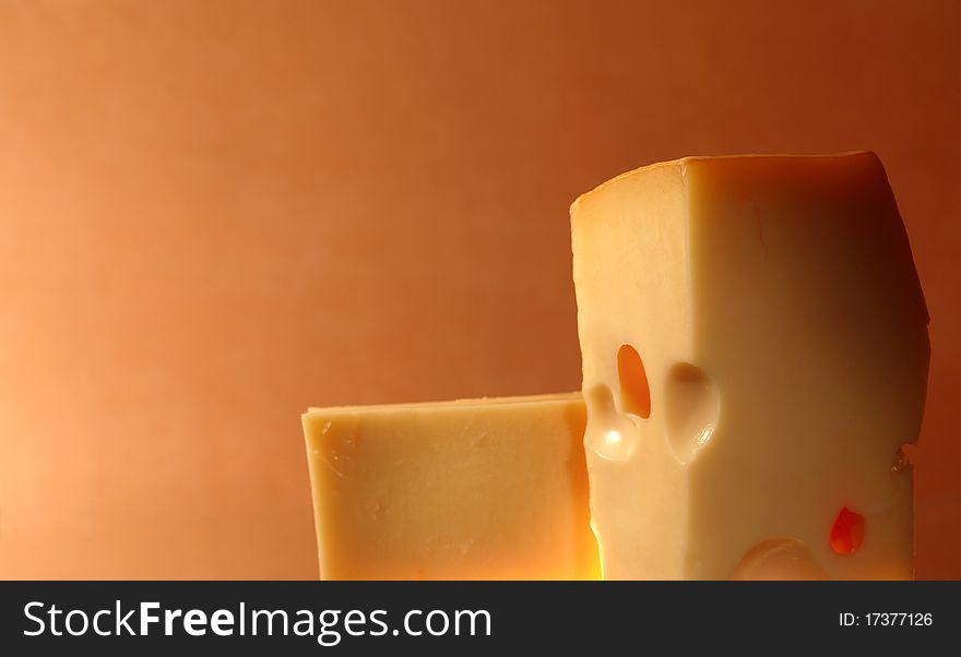 Two pieces of cheese against colorful gradient background with copy space