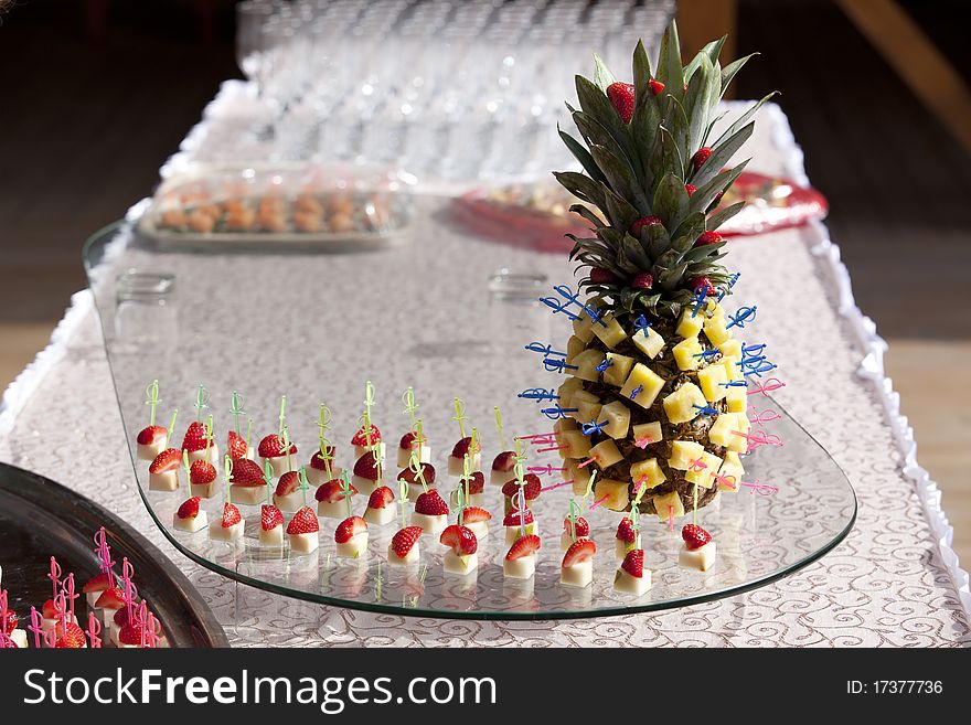 Pineapple and strawberries on skewers. Table appointments outdoors.