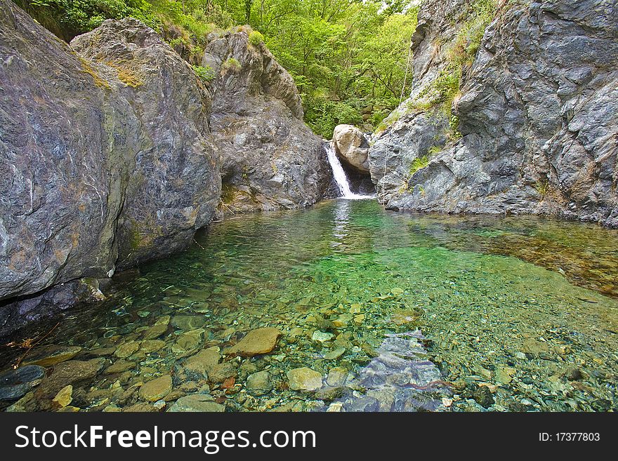 Small lake and fall between the high rocks of the river canyon, with rope for canyonists, italy. Small lake and fall between the high rocks of the river canyon, with rope for canyonists, italy