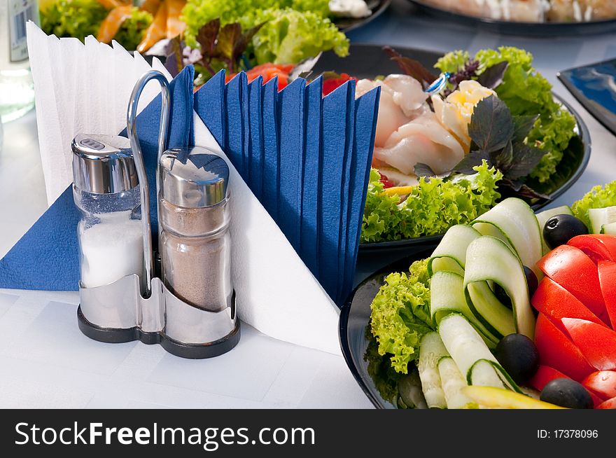 Tableware, paper napkins, salt, spices and appetizer on a table. Tableware, paper napkins, salt, spices and appetizer on a table.