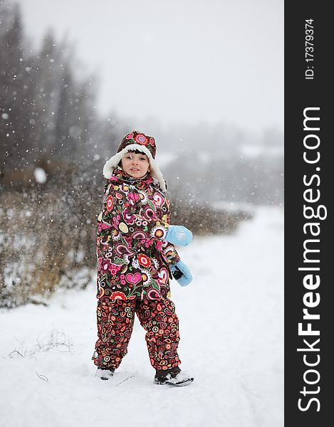 Adorable small girl in colorful winter clothes plays with snow in strong snowfall. Adorable small girl in colorful winter clothes plays with snow in strong snowfall