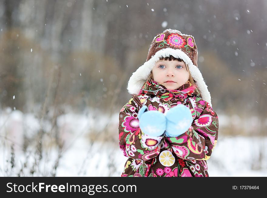 Adorable small girl in colorful winter clothes plays with snow in strong snowfall. Adorable small girl in colorful winter clothes plays with snow in strong snowfall