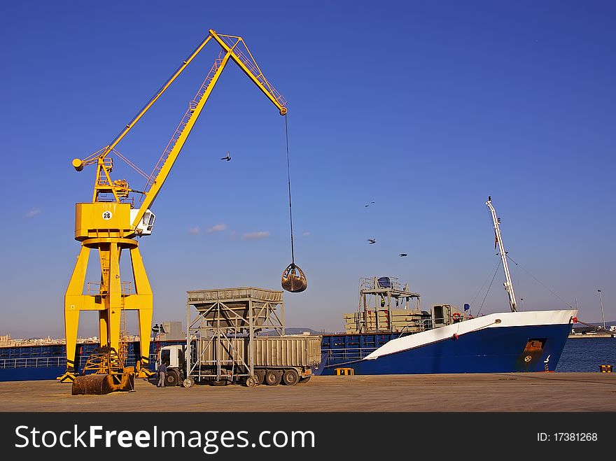 Unloading a cargo ship in the dock with a crane. Unloading a cargo ship in the dock with a crane