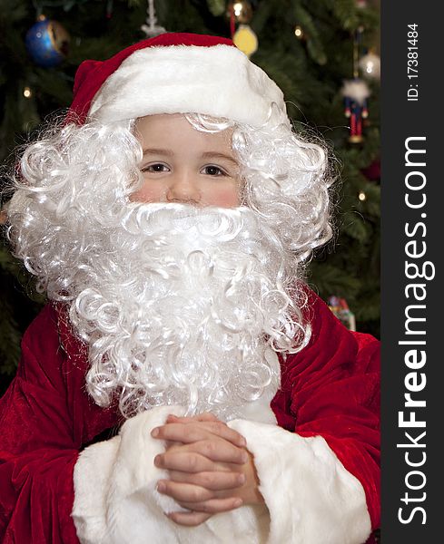 Young boy in front of Christmas tree wearing a Santa Claus suit. Young boy in front of Christmas tree wearing a Santa Claus suit.