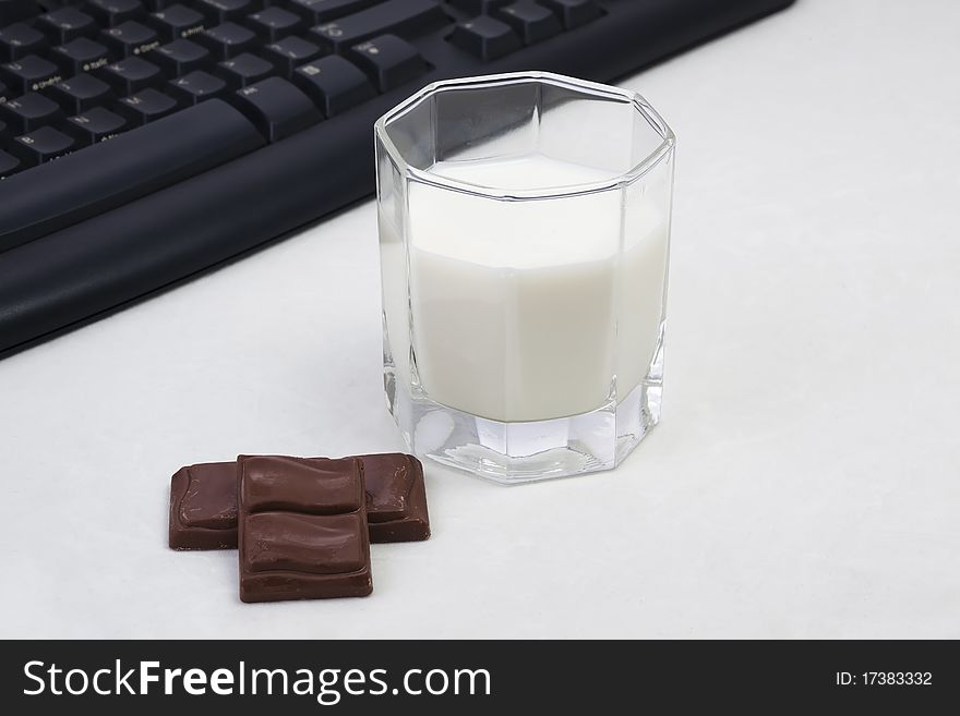 A glass of milk and two chocolate in the white background. A glass of milk and two chocolate in the white background