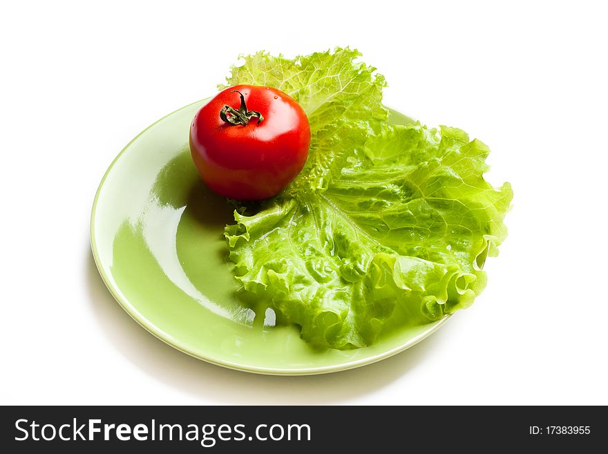 Red tomato and green lettuce on a dish. Red tomato and green lettuce on a dish