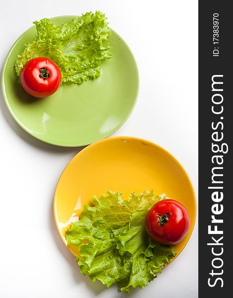 Red tomatoes and green lettuce on a dish. Red tomatoes and green lettuce on a dish