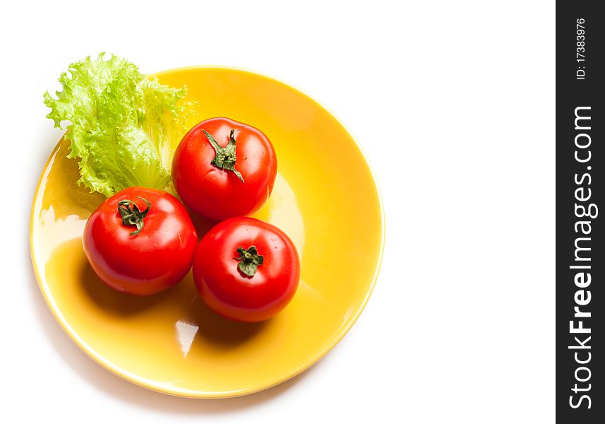 Red tomatoes and green lettuce on a dish. Red tomatoes and green lettuce on a dish