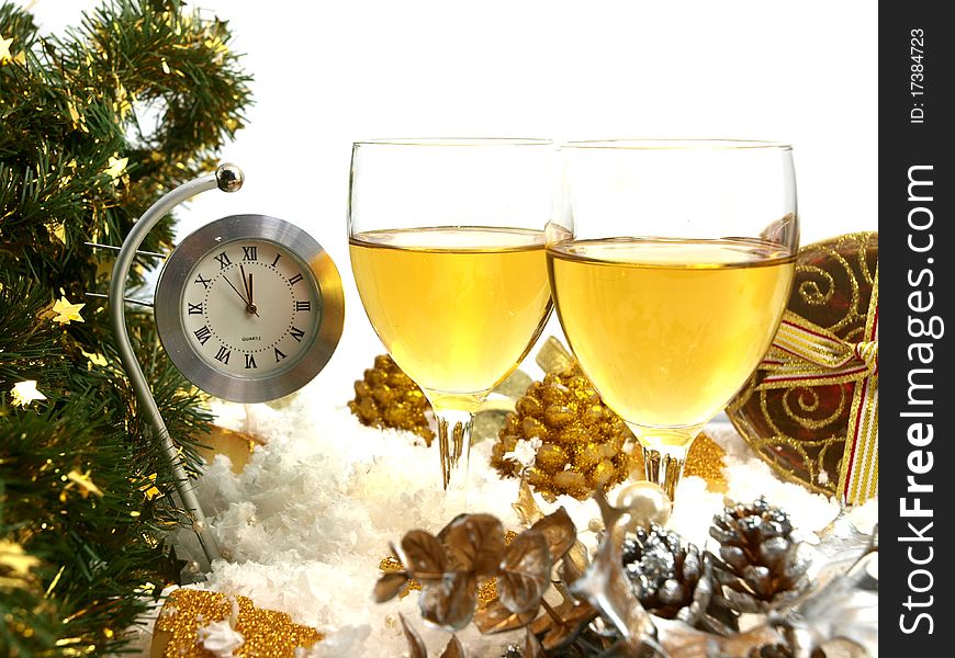 Clock showing twelve, two glasses with wine