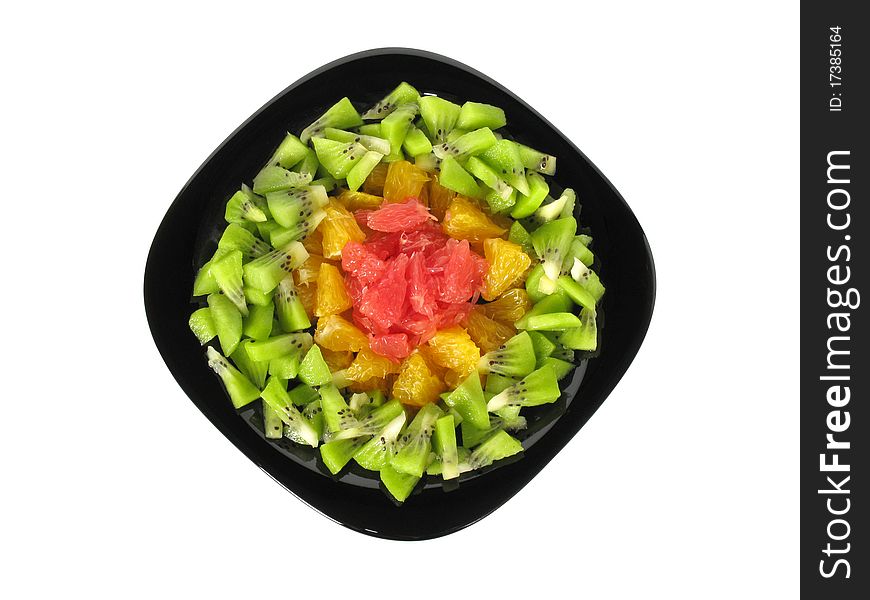 Fruit salad (fruit slices on a black dish isolated on white background).