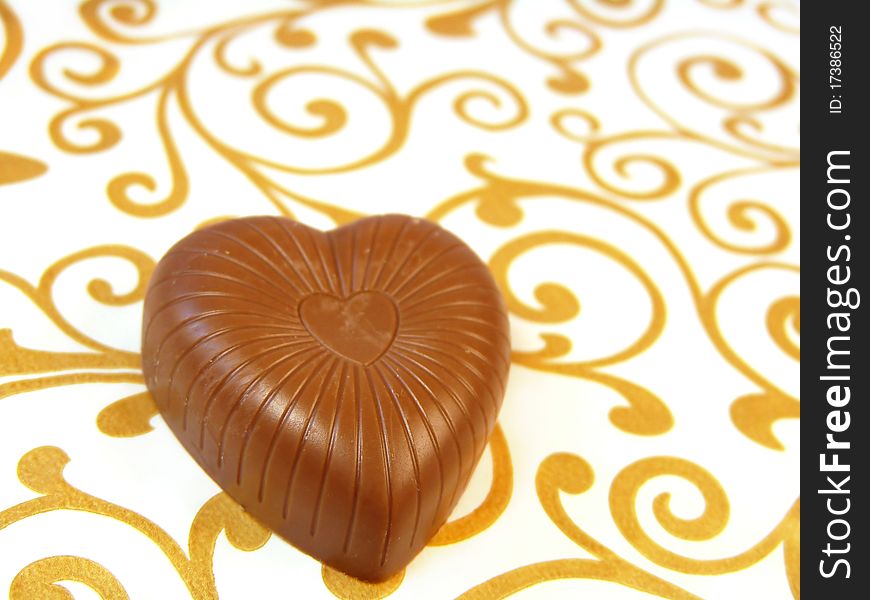 Mouthwatering chocolates in a heart-shaped on a colored background