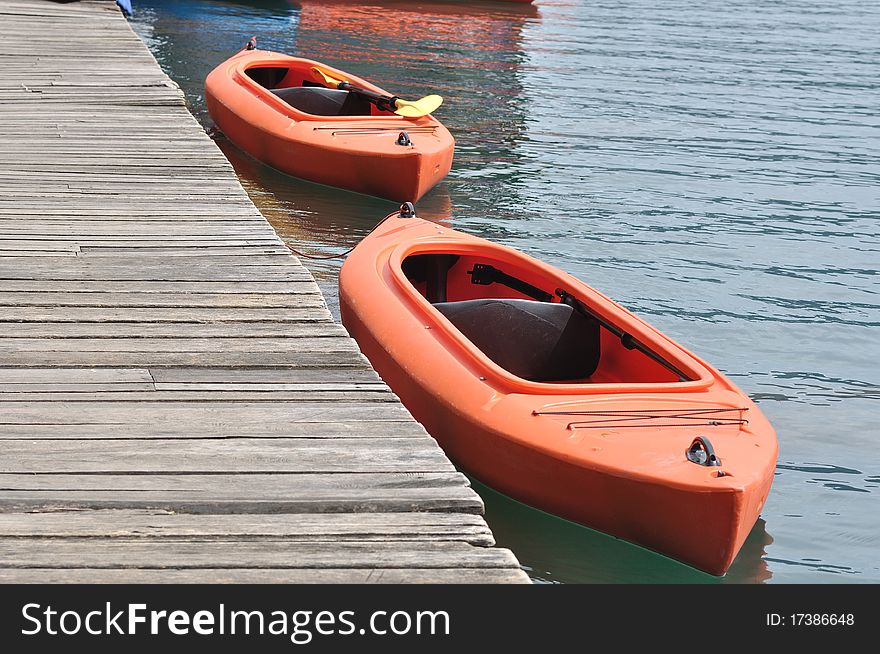 Two orange kayak beside wooden dock.