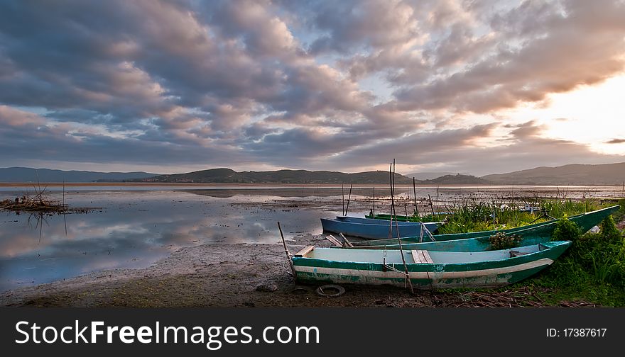 Old fishing boats on lake shore at dawn, Italy