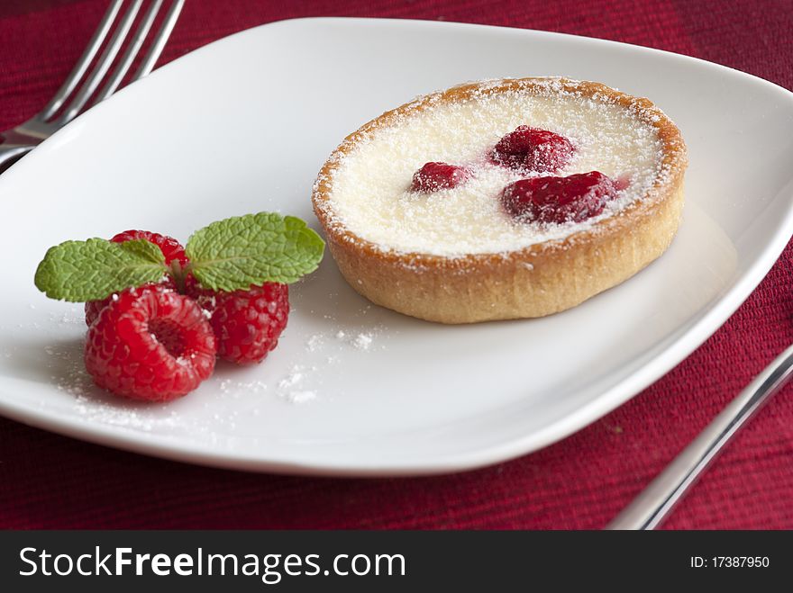 Raspberry and custard tart decorated with fresh mint. Raspberry and custard tart decorated with fresh mint