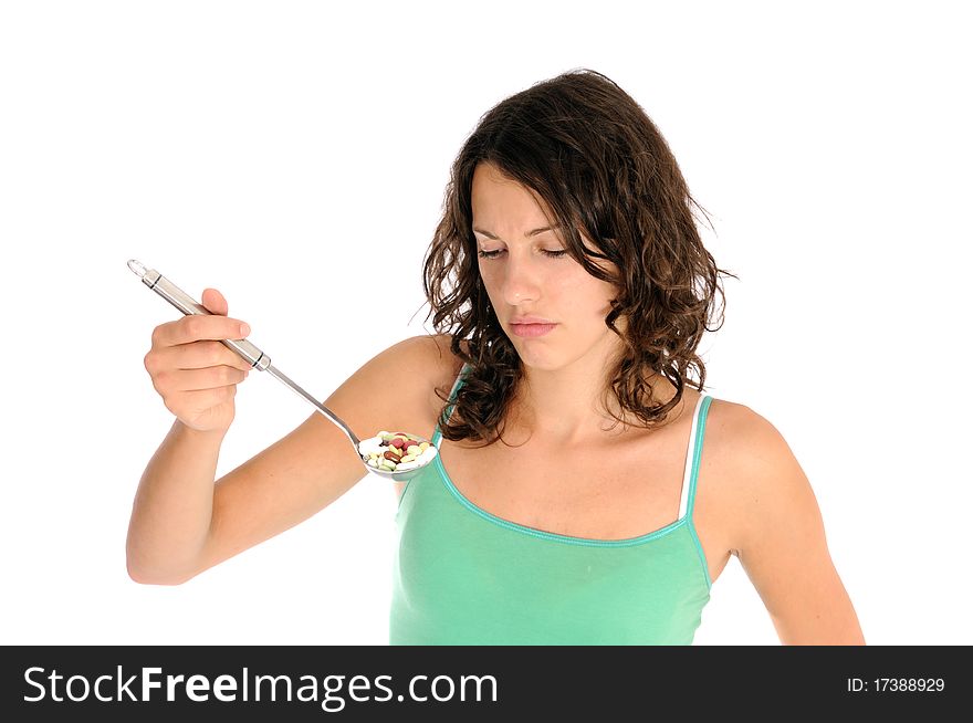 Pretty young woman holding spoon with pile of pills looking skeptical. Concept shot for drug abuse or alternative medicine.