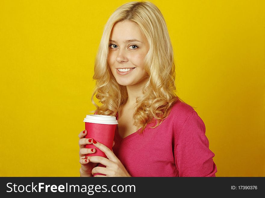 Beautiful young woman on a yellow background holding a paper cup of coffee. Beautiful young woman on a yellow background holding a paper cup of coffee