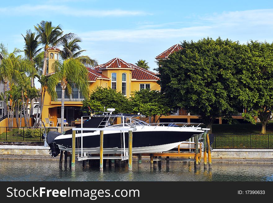 Rearview of a luxurious waterfront home located in a beautiful neighborhood with tropical landscaping. High powered, deep sea and flats fishing boats seen on davits in the canal. Rearview of a luxurious waterfront home located in a beautiful neighborhood with tropical landscaping. High powered, deep sea and flats fishing boats seen on davits in the canal.