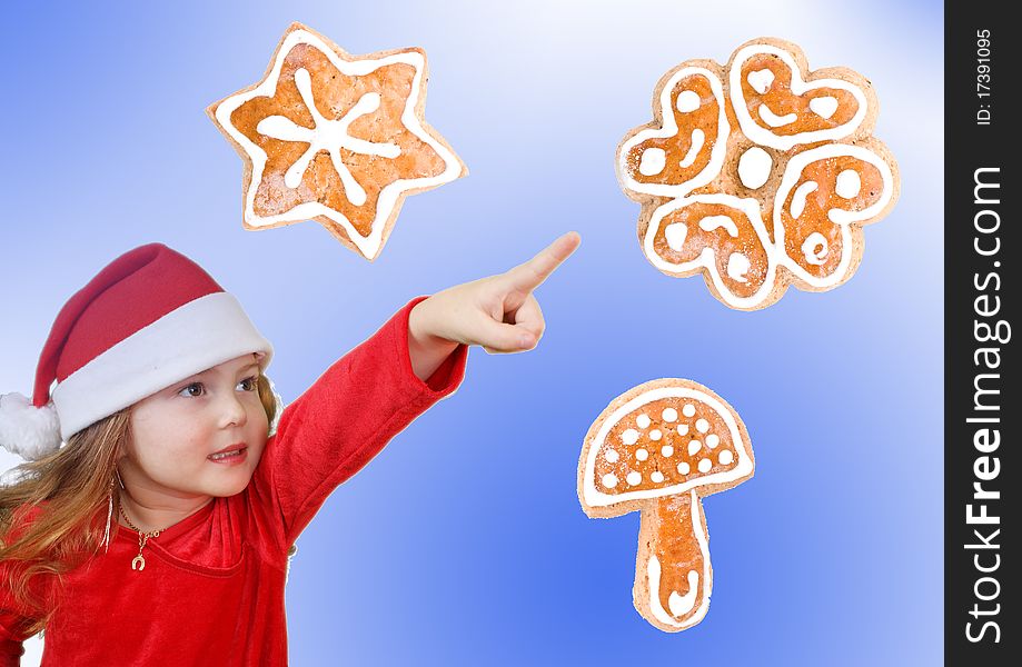 Little girl in Christmas hat pointing to cookie, isolated on white