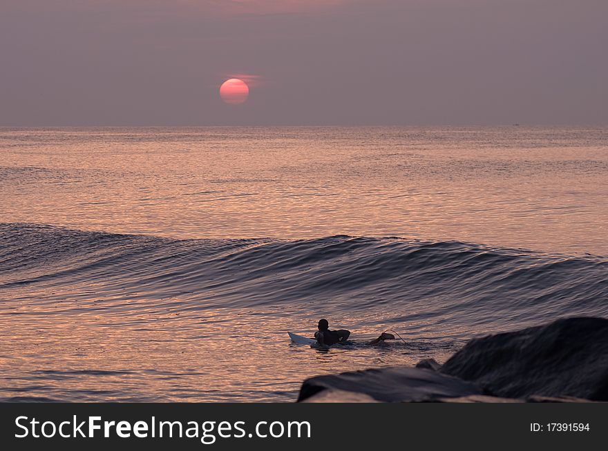 Silhouetted surfer catching wave at sunrise. Silhouetted surfer catching wave at sunrise