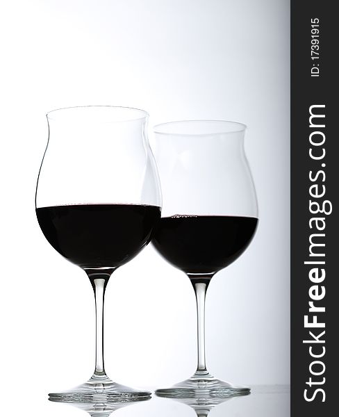 Two red wine glasses half full on a white background