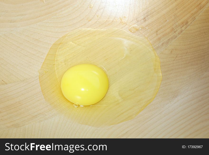 A broken egg in a wooden bowl