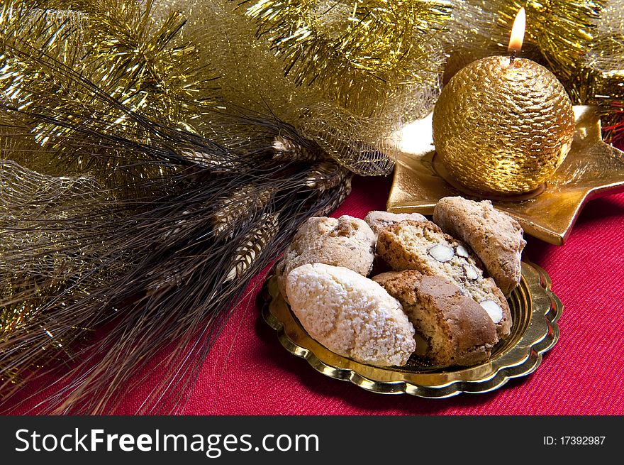 Biscuits and golden candle and Christmas decorations on red background