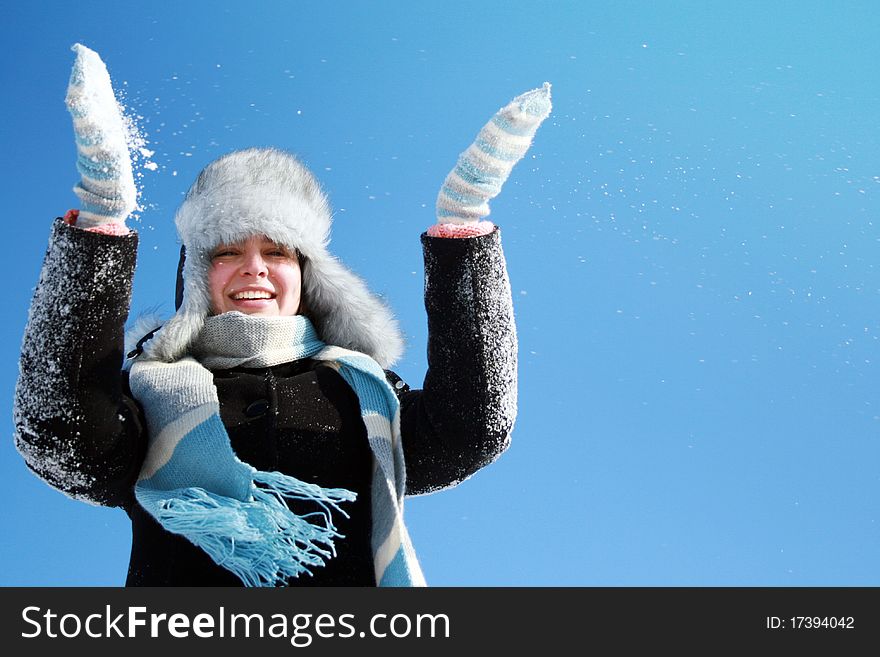 Woman making snowfall against blue sky