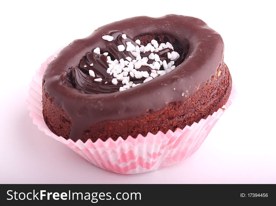Chocolate cupcake decorated with chocolate frosting and white sugar sprinkles isolated on white background