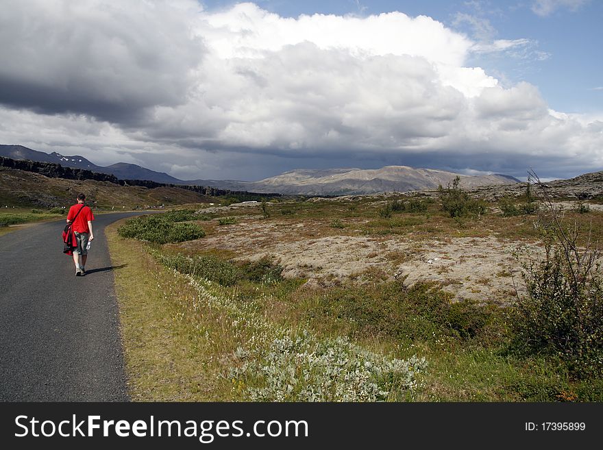 Lonely male traveller walking along the street and hitch-hiking  in Iceland