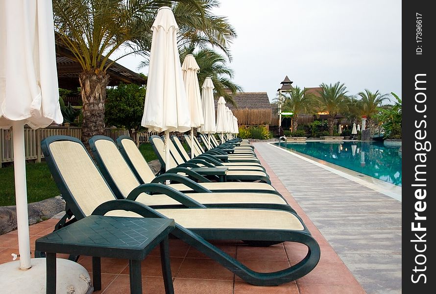 Chaise longue and umbrellas near the swimming pool. Chaise longue and umbrellas near the swimming pool.