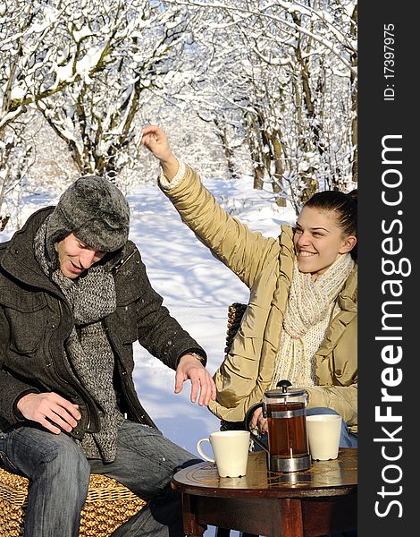 Young man and woman celebrating winter season, cups with tea on table. Young man and woman celebrating winter season, cups with tea on table