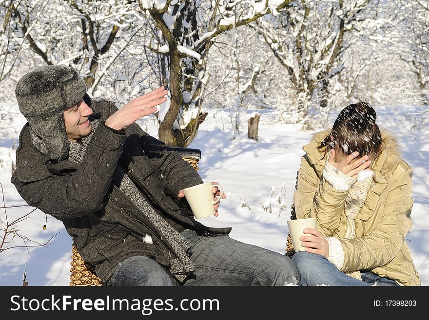 Teenager boy and girl drinking tea in winter season, snow on branches in background. Teenager boy and girl drinking tea in winter season, snow on branches in background