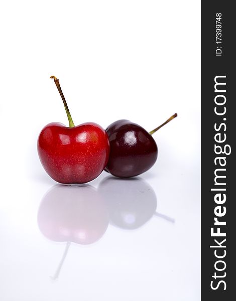 Two fresh cherries isolated on white background with reflection in foreground.