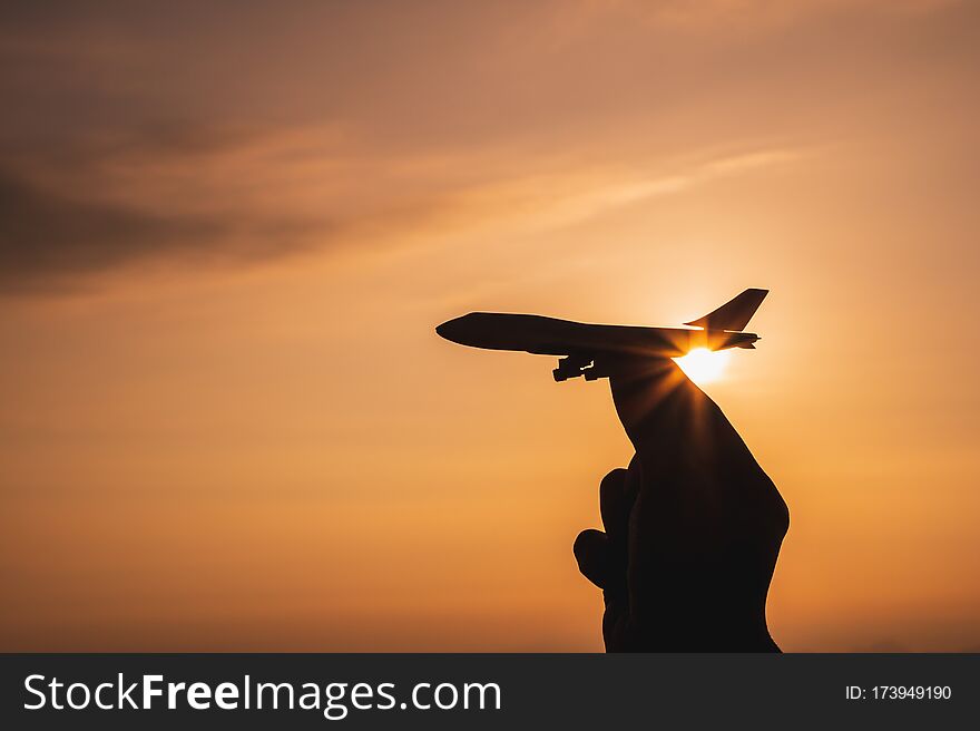 A Hand Holding A Toy Plane Go To The Sky With Sunset Light