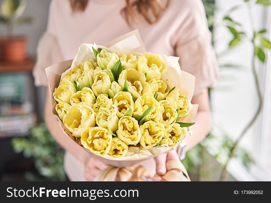 Yellow pastel color tulips in woman hand. Young beautiful woman holding a spring bouquet. Bunch of fresh cut spring flowers in female hands.