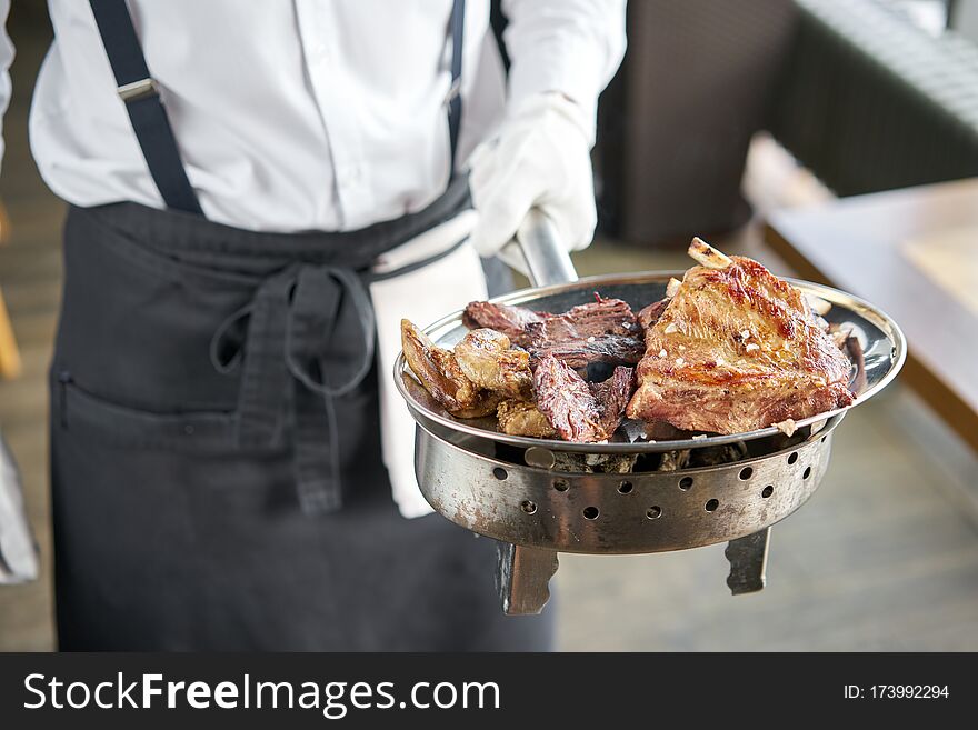 The waiter is holding a plate Various grilled meat set. Barbecue restaurant menu, a series of photos of different meats.