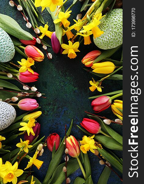 Easter eggs and tulips and daffodils on rustic background. Springtime decoration for easter