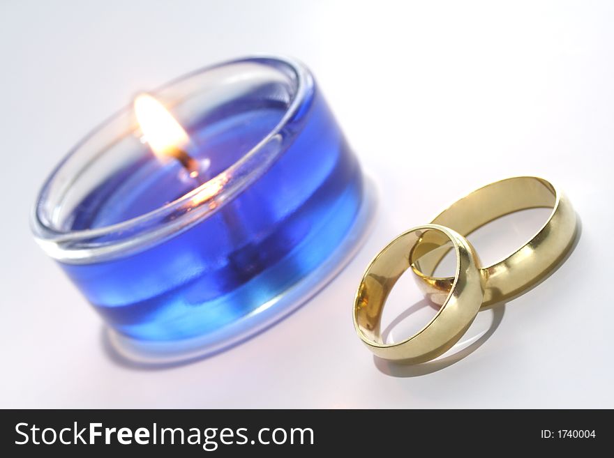 Gold wedding rings with blue burning candle. Gold wedding rings with blue burning candle