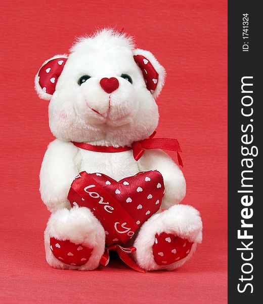 Teddy bear with red valentine heart on red background