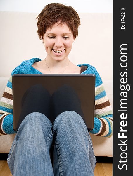 Cute girl with her laptop back against the couch. Cute girl with her laptop back against the couch