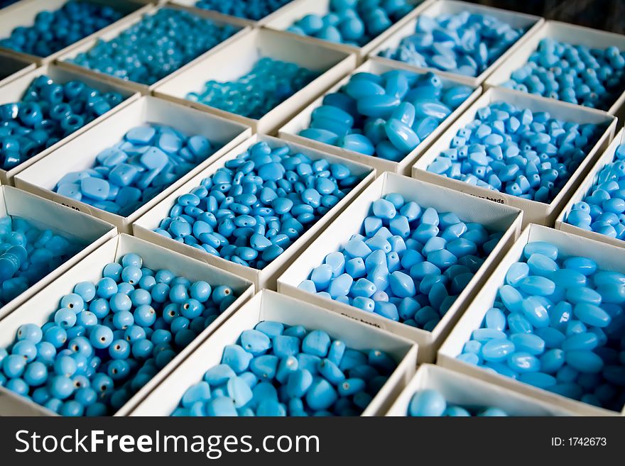 Arrayed boxes containing different types of blue beads. Narrow DoF.