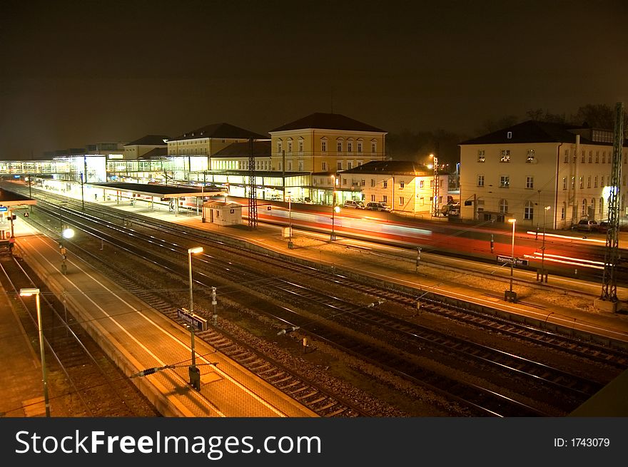 The railway station at Regensburg Germany, at night - with a train leaving.