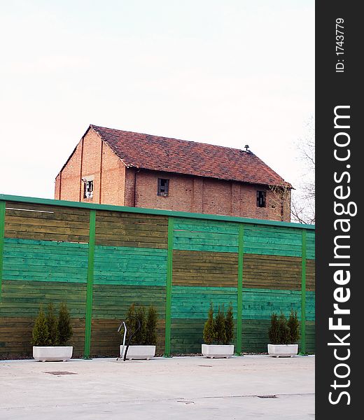 Red house behind wooden green fence