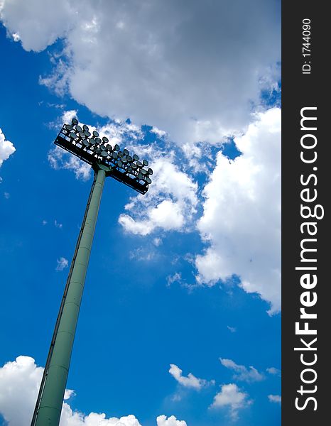 Stadium  lights with blue sky and clouds above. Stadium  lights with blue sky and clouds above.
