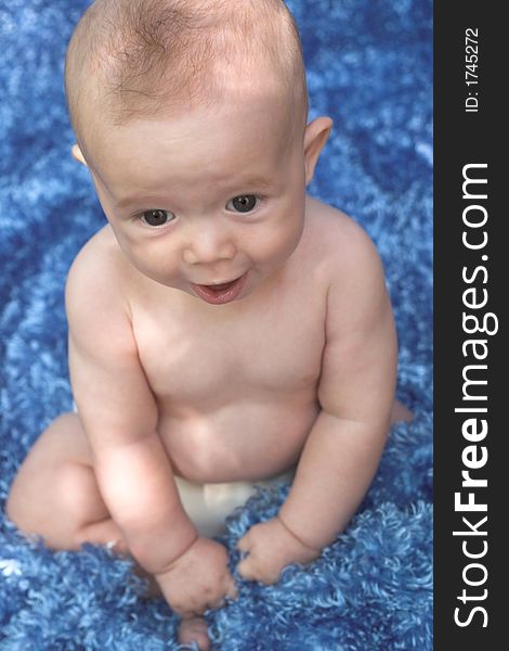 Image of smiling baby boy sitting on a blue blanket