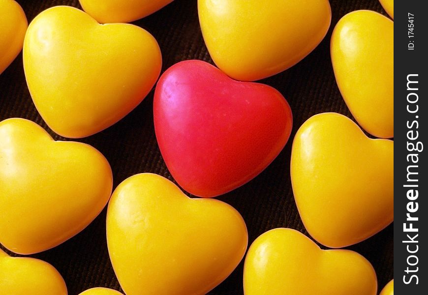 Pink candy heart surrounded by yellow hearts.