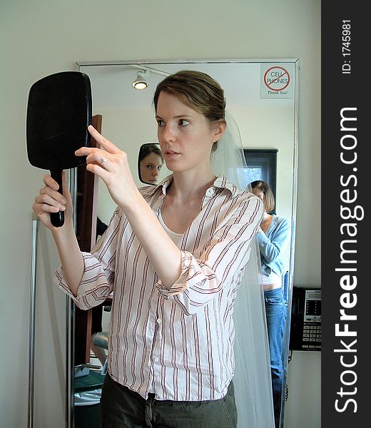 Bride examining her reflection with veil at beauty salon. Bride examining her reflection with veil at beauty salon