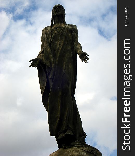 A bronze sculpture of Jesus on air over a cloudy sky. A bronze sculpture of Jesus on air over a cloudy sky